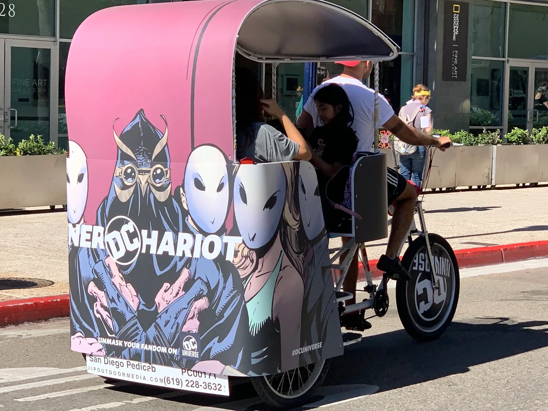 DC Universe Nerd Chariot pink pedicab with passengers at Comic-Con