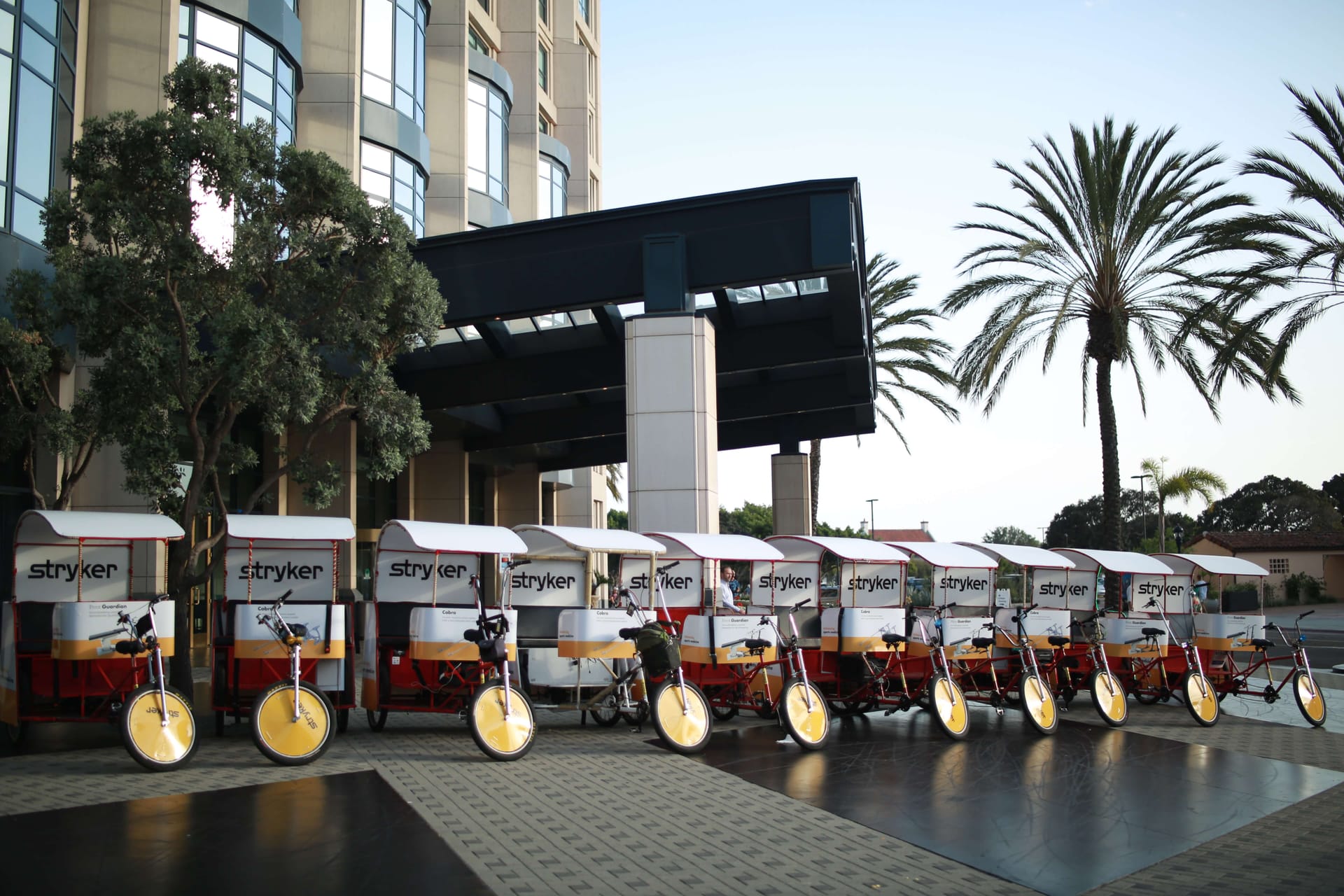 Stryker branded pedicab fleet lined up outside a San Diego hotel in the evening